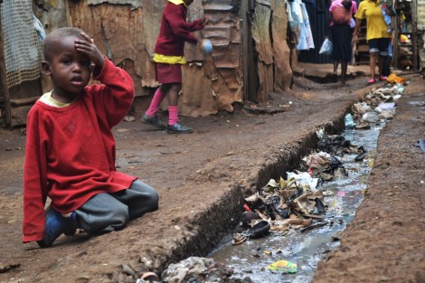 A young boy sits over an open sewer in the Kibera slum, Nairobi.
